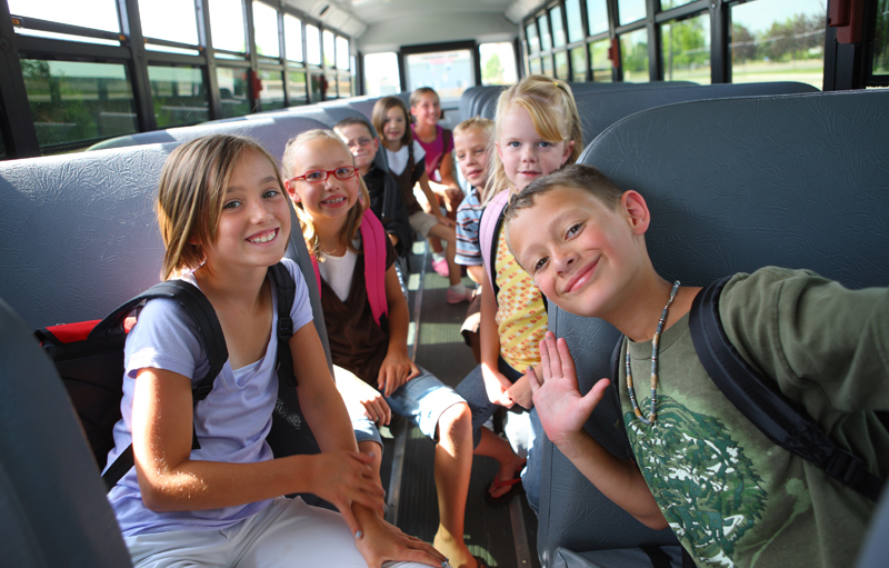 תלמידי בית ספר נוסעים באוטובוס הסעות ומחייכים למצלמה