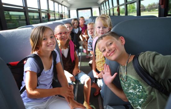 תלמידי בית ספר נוסעים באוטובוס הסעות ומחייכים למצלמה